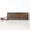 Fertiges Fadenbild „Miteinander“ auf dunklem Holzbrett