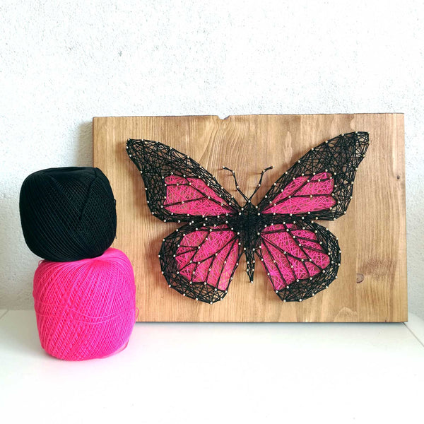 Schmetterling wird beim Fädeln auf Holzbrett gestaltet